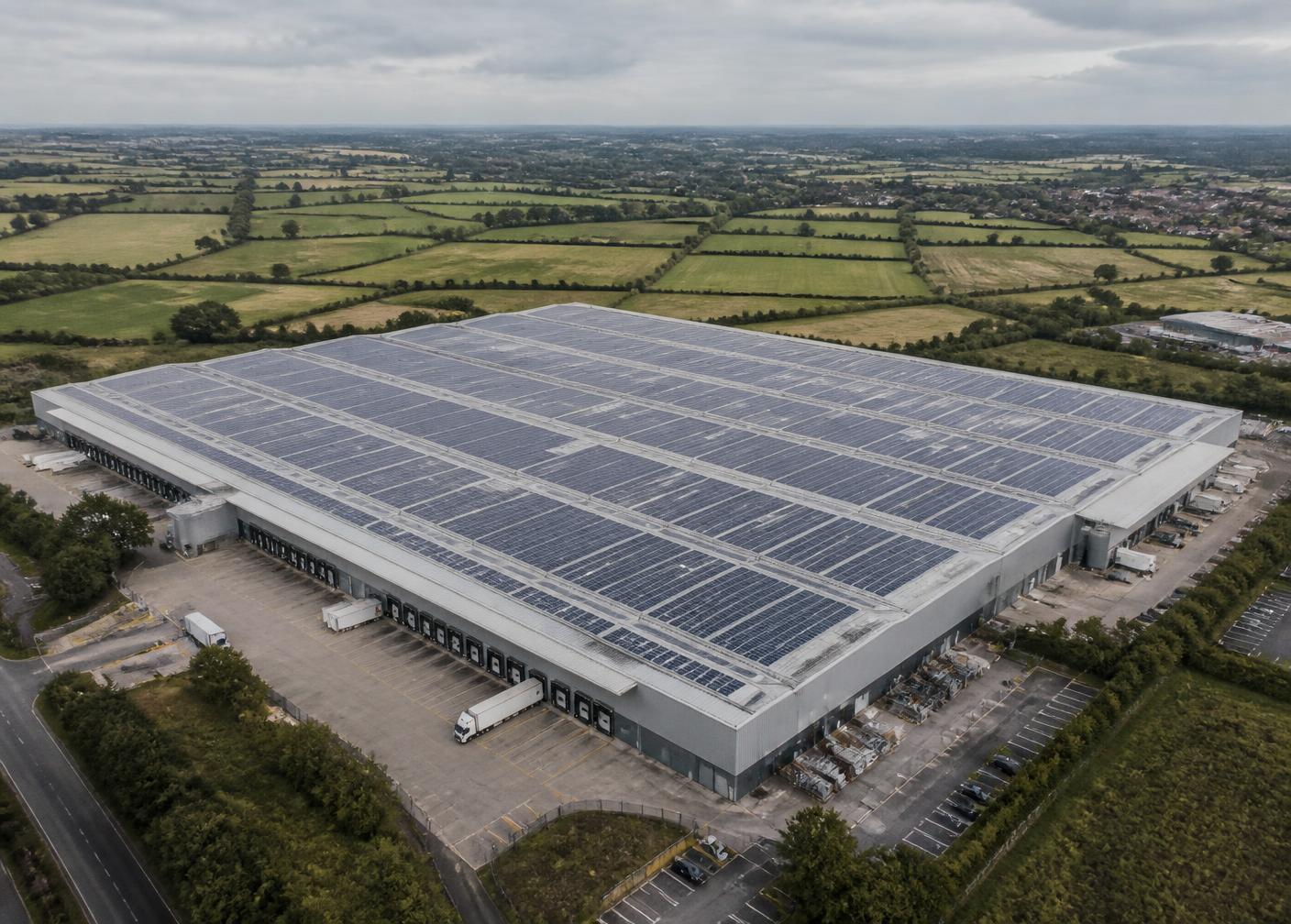 Aerial view of a large warehouse roof covered in a commercial solar array