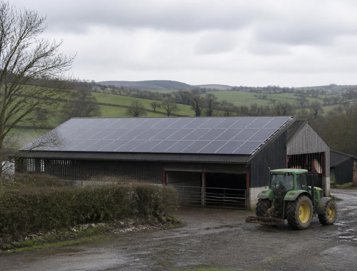 Solar panels covering a farm barn roof with a tractor parked alongside