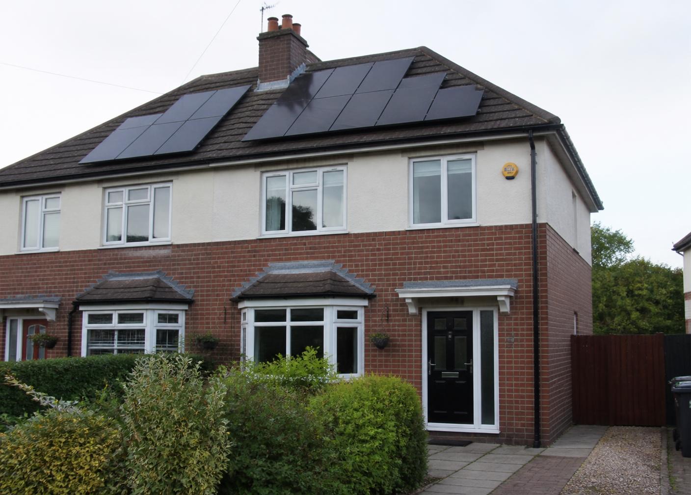 Black solar panels fitted to the pitched roof of a UK semi-detached house
